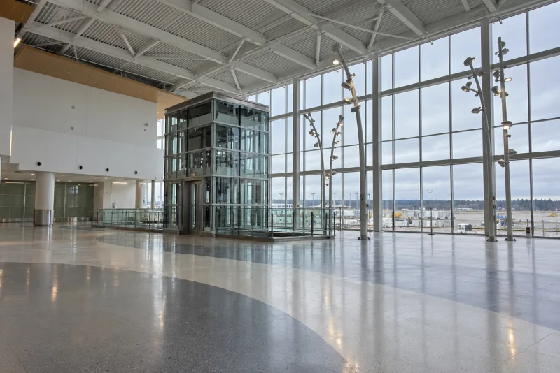 The tall glass wall and white lamp posts at the end of the North Satellite hall at Seattle-Tacoma airport.