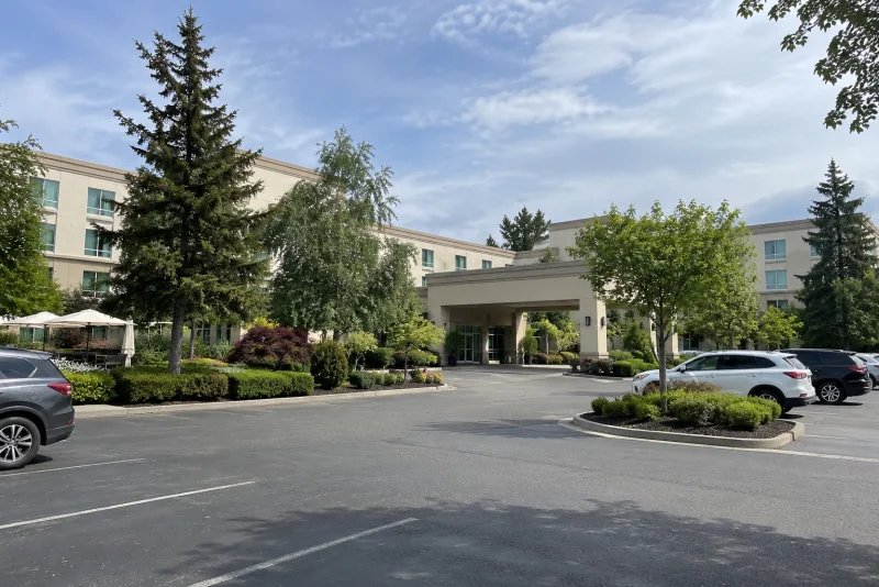 A pale low-rise airport hotel with a covered entrance among trees near Seattle-Tacoma airport.