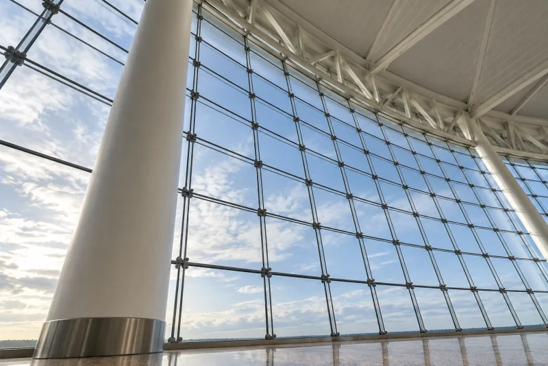 A white column and the tall curved glass wall of the Central Terminal food hall at Seattle-Tacoma airport.