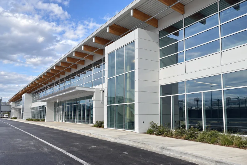 The pale paneled Concourse D Annex building with its sloping timber-edged roof beside a roadway at Seattle-Tacoma airport.