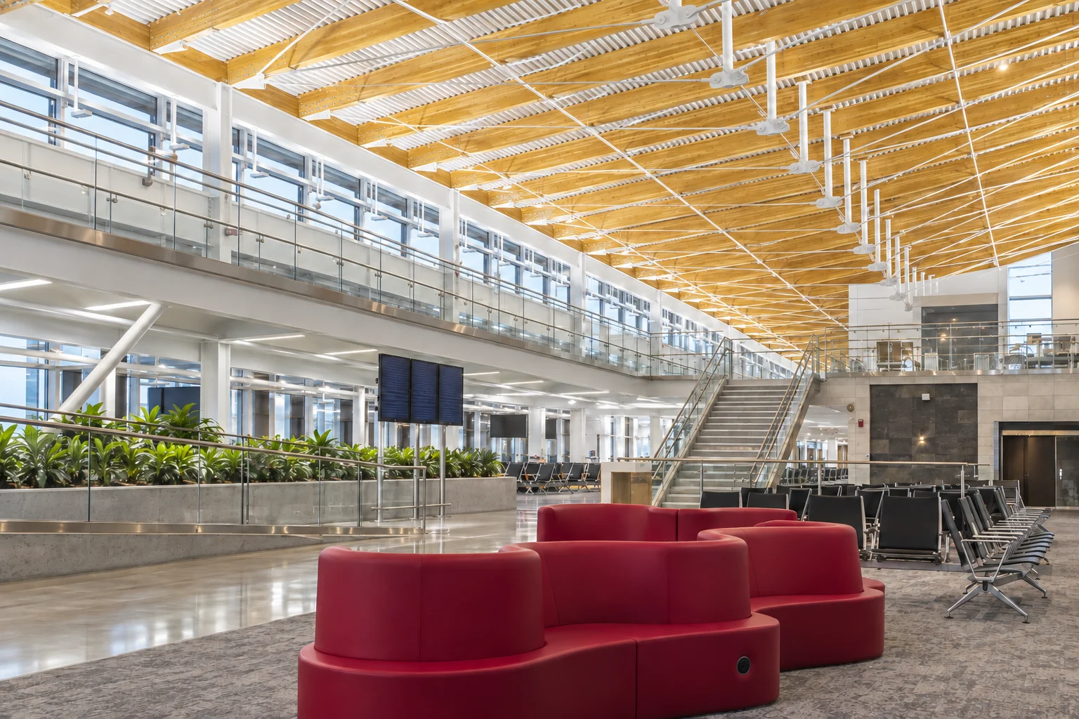 The timber roof, glass mezzanine and red seating inside SEA’s completed Concourse D Annex