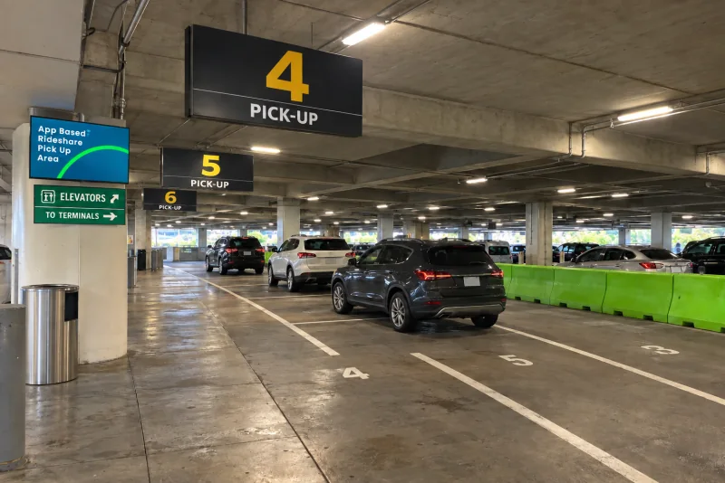 The rideshare pickup area in the garage with Pick-Up 4 and 5 signs and the green barrier.