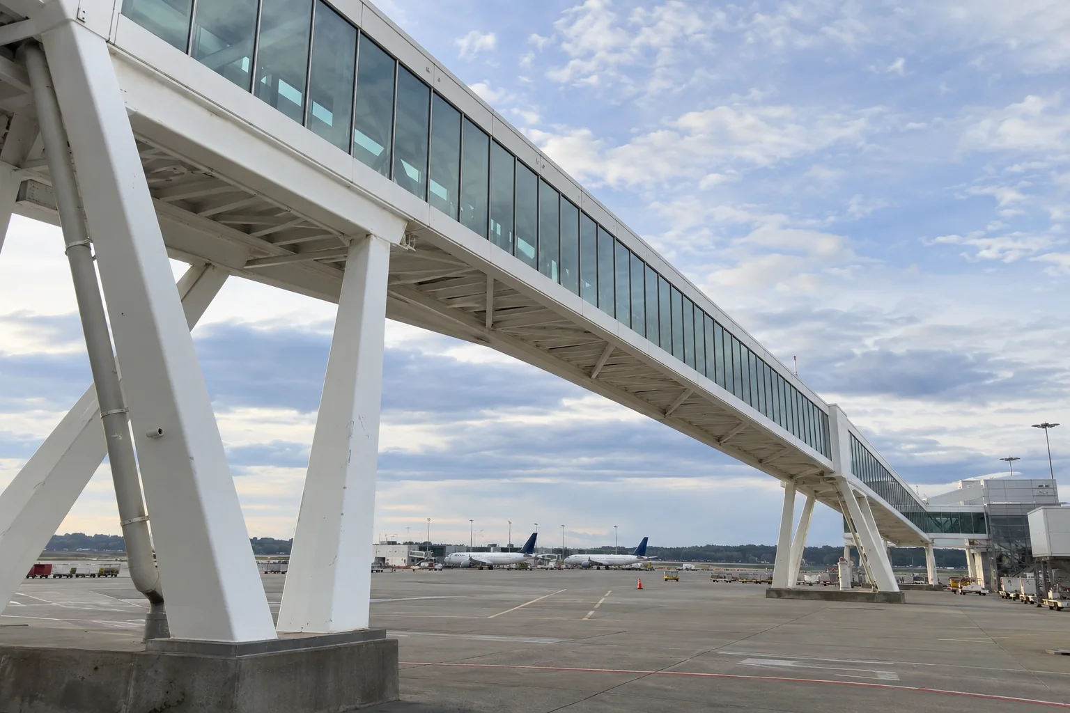 The white glass-sided pedestrian sky bridge on angled supports above the apron at Seattle-Tacoma airport.