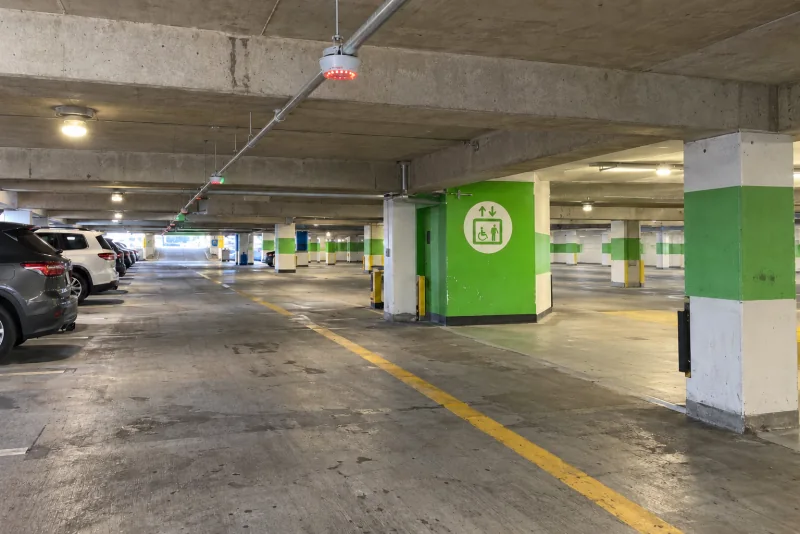 A covered level of the Seattle-Tacoma airport parking garage, with parked cars and a bright green elevator core