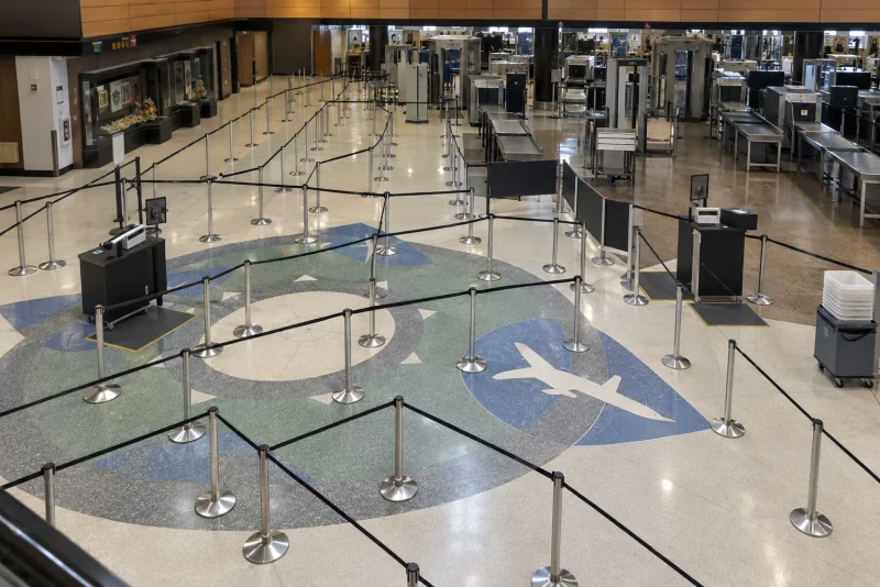 The empty rope-and-stanchion lanes of a security checkpoint queue, with the airplane shape inlaid in the floor and the screening lanes beyond.