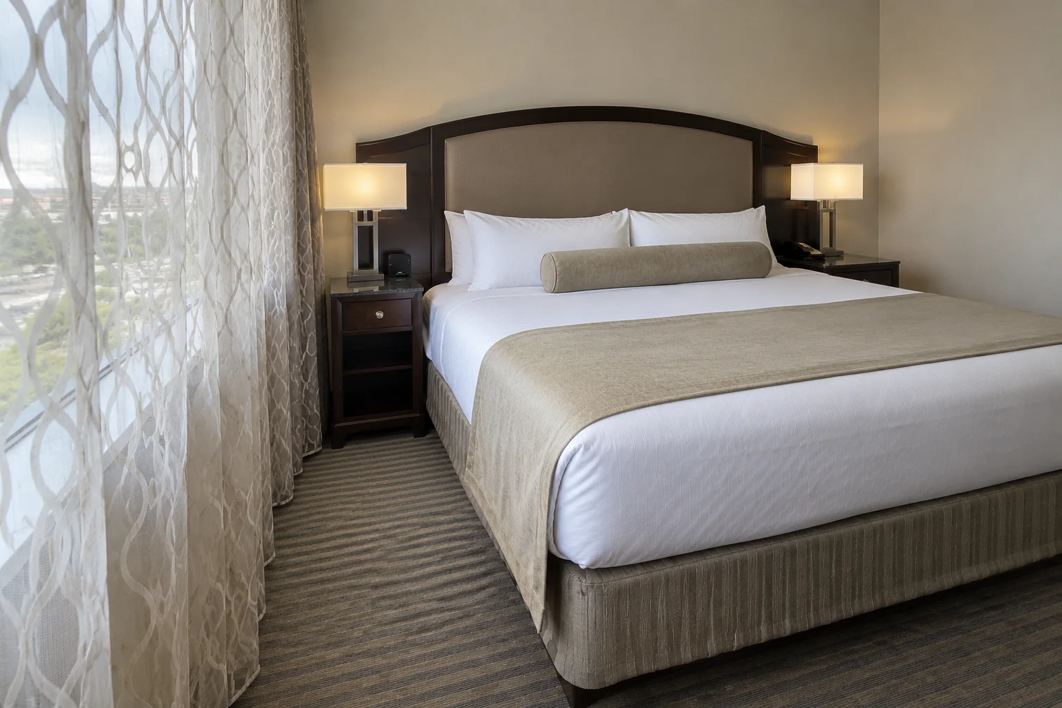 A made king bed with white linens and a dark wood headboard in a hotel room near Seattle-Tacoma airport.