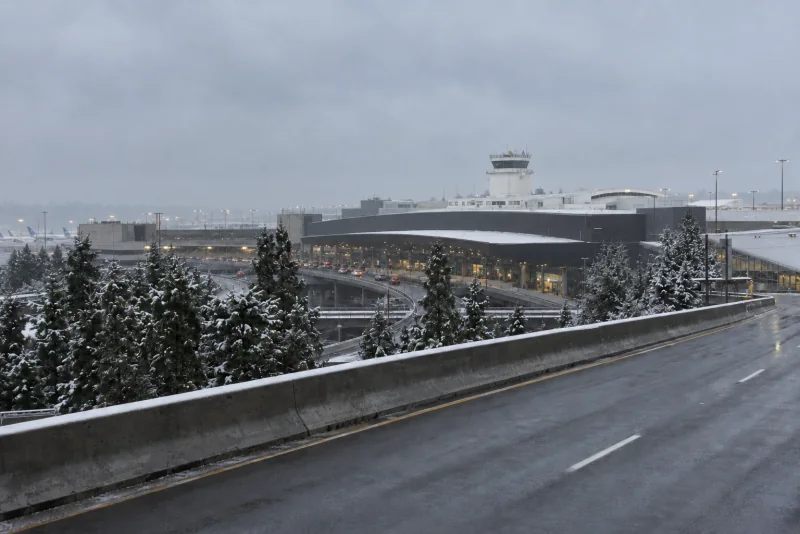The Seattle-Tacoma airport terminal and control tower under low grey cloud on a snowy day.