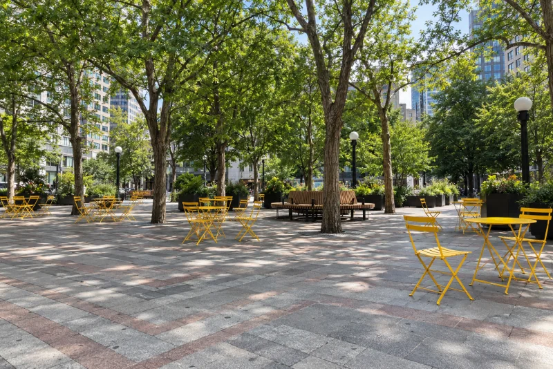 Westlake Park in downtown Seattle with folding chairs on chevron granite paving under trees.