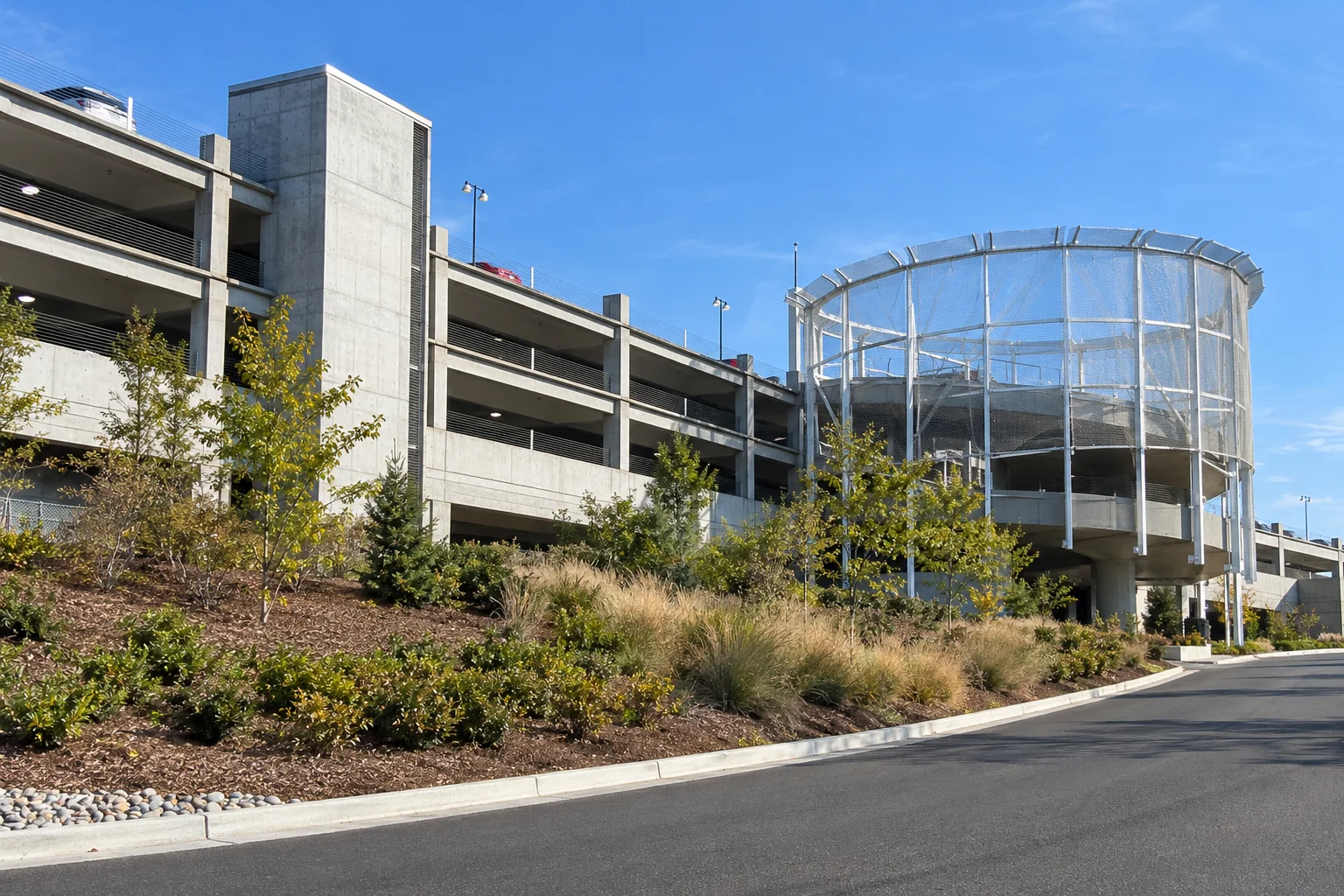 The curved wire-mesh ramp tower and grey concrete garage of the Rental Car Facility beside the road near Seattle-Tacoma airport.